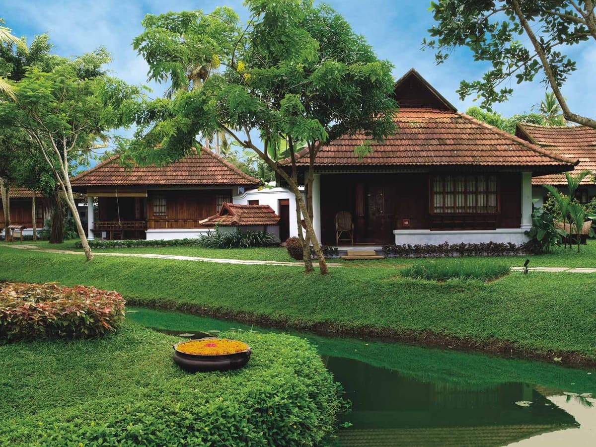 Traditional wooden cottages with tiled roofs set in a lush garden with a small stream.